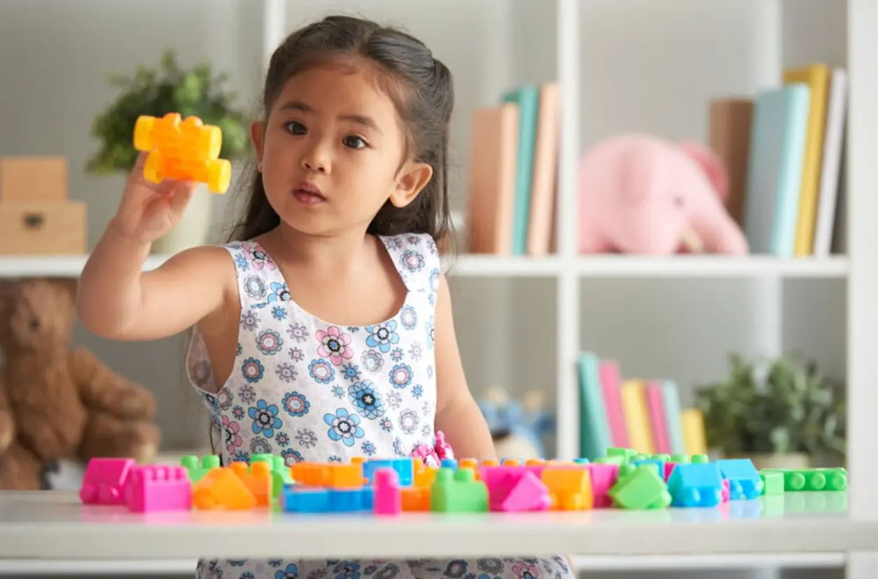 Young girl playing with colorful building blocks